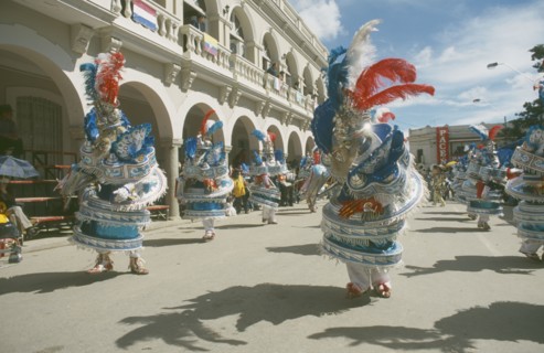 BOLIVIA, Oruro, Carnival masqueraders in colourful animal costumes in a street lined with colonial