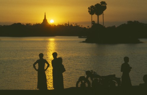 MYANMAR, Yangon, People silhouetted on shore of lake looking across towards the Shwedagon Pagoda at