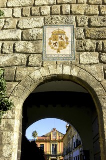 SPAIN, Andalucia, Seville, The Royal Alcazar. Stone archway with the coat of arms above