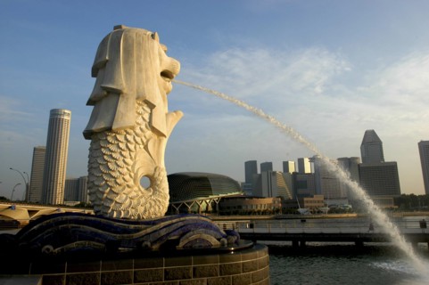 SINGAPORE, Merlion, Merlion statue spouting water over Singapore River in evening light with the