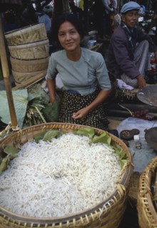 MYANMAR, Markets, Young woman selling noodles on market stall near Inle Lake.