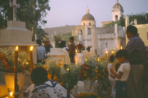 MEXICO, Puebla, Acatlan, People keeping vigil beside graves decorated with candles and flowers