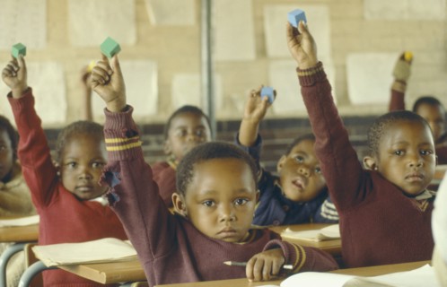 SOUTH AFRICA, Gauteng, Soweto, Classroom scene.  Young pupils raising hands.