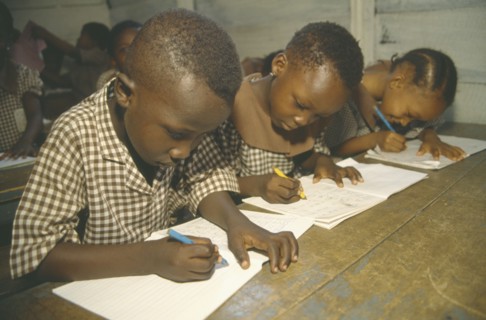 GHANA, Accra, Primary school pupils writing at their desks.