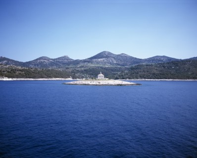 CROATIA, Dalmatia, View over water toward small islet between Sibenik and Trogir with lighthouse in