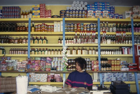 DOMINICAN REPUBLIC, Shop, Woman behind counter in general store in front of goods on shelves behind