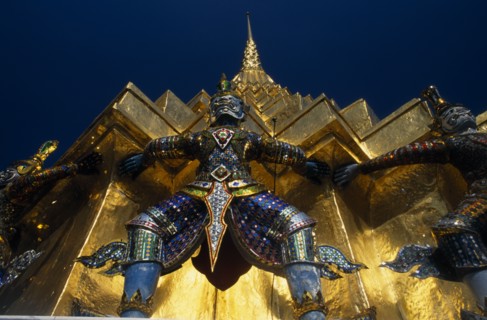 THAILAND, Bangkok, Grand Palace. Demon statue at the base of a spire or prang.