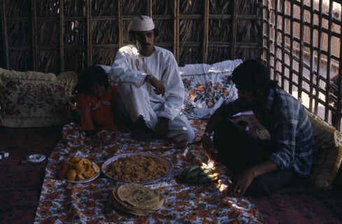 OMAN, Food, Two men and girl sitting with a meal served in communal dishes in front of them.
