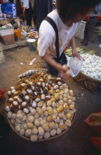 CHINA, Yunnan, Kunming, Covered food market  with baskets filled with thousand year old eggs.