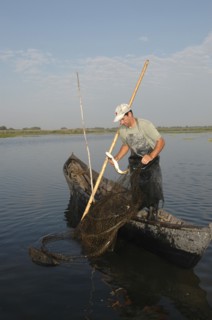 ROMANIA, Tulcea, Danube Delta Biosphere Reserve, Professional fisherman in canoe on Lake Isac