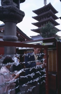 JAPAN, Honshu, Tokyo, Asakusa. People tying Omikuji or Fortune papers at Senso Ji Temple