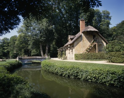 FRANCE, Ile de France, Paris, Versalilles Hameau de Trianon. View over river towards thatched