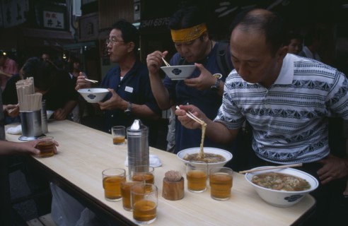 JAPAN, Honshu, Tokyo, Tsukiji Fish Market. People eating with chopsticks at noodle stall