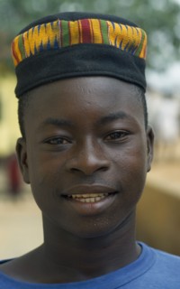 GHANA, Tribal People, Portrait of boy wearing hat made from traditional kente cloth.