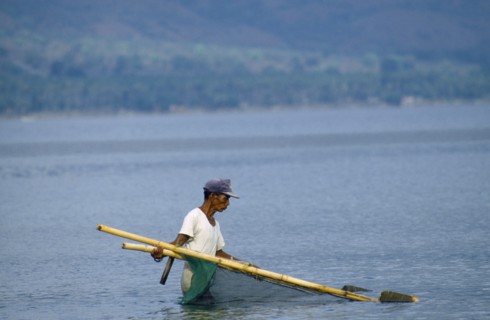 INDONESIA, Palu, Man fishing near beach with hand net
