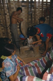 LAOS, Markets, Hmong village.  Building interior with people making rice balls.