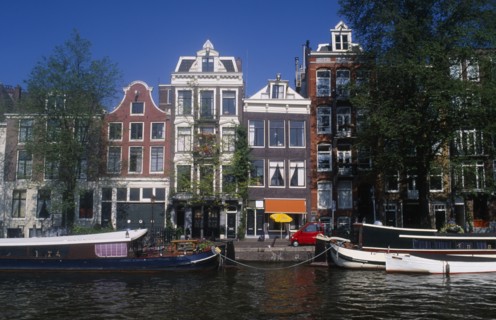 HOLLAND, Noord, Amsterdam, Moored barge on the side of the Oude Schans canal lined with traditional