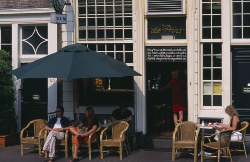 HOLLAND, Noord, Amsterdam, Brown Cafe facade with couple sitting outside