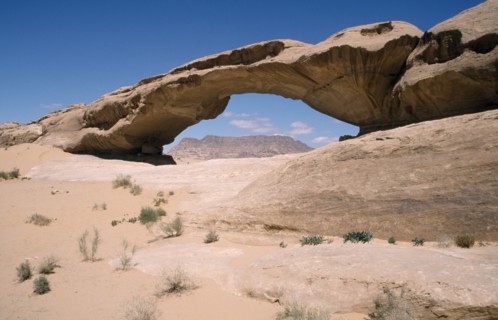 JORDAN, Wadi Rum Desert, Rock formation in the form of natural arch framing view to distant flat