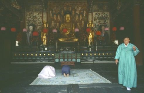 SOUTH KOREA, Kyansu, Pulguk-Sa temple.  Interior with worshippers praying in front of seated Buddha