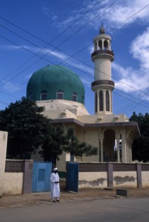 NIGERIA, Kano, Mosque with green dome. Man stood outside the open gate.
