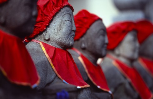 JAPAN, Honshu, Kamakura, View along row of Jizo statues dressed in red bibs by bereaved mothers and