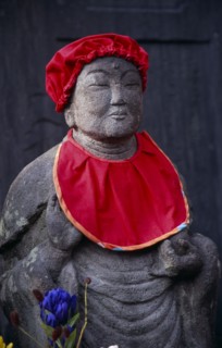 JAPAN, Honshu, Kamakura, Jizo statue traditionally dressed in red bibs by bereaved mothers and