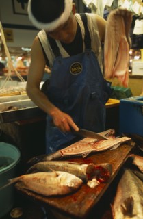 JAPAN, Honshu, Tokyo, Tsukiji Fish Market with man slicing a fish in half