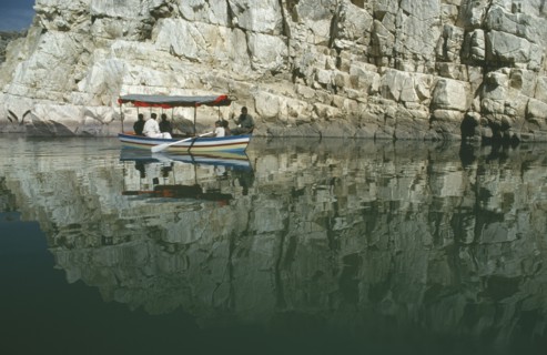 INDIA, Madhya Pradesh, Marble Rocks, Painted tourist boat on the Narmada River passing sheer cliffs