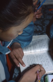 CHINA, Yunnan Province, Schoolgirl reading her book in class.