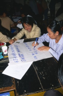 CHINA, Yunnan Province, Simao. Pu’er. Teachers sat around a table preparing a presentation on flip
