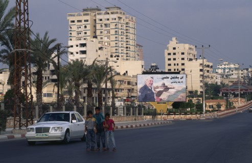 GAZA STRIP, Gaza City, Children on quiet road with billboard of Yasser Arafat and city buildings