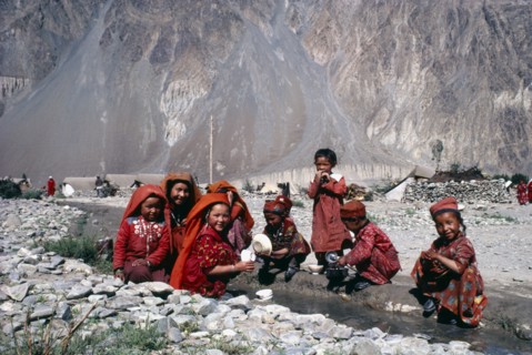AFGHANISTAN, Tribal People, Kirghiz woman and children laughing as they wash pots in fresh water