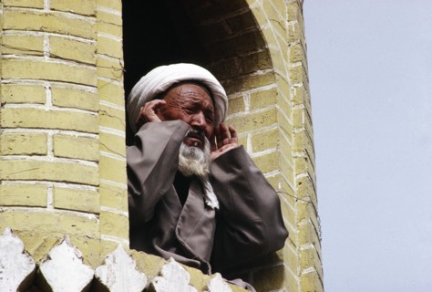 CHINA, Xinjiang Province, Kashgar, Muezzin at call to prayer from minaret of mosque.