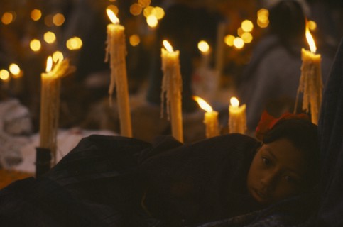 MEXICO, Festivals, Young girl holding candle lit graveside vigil for Day of the Dead. Dia de los
