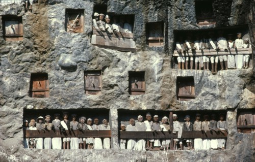 INDONESIA, Sulawesi, Toraja wooden funeral effigies or tau tau in cliff graves.  The figures