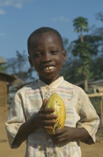 GHANA, West, Children, Portrait of child holding cocoa pod.