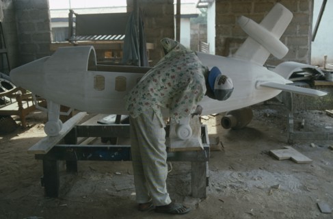 GHANA, Teshie, Kane Kwei brothers workshop.  Man painting and gluing together the wooden sections