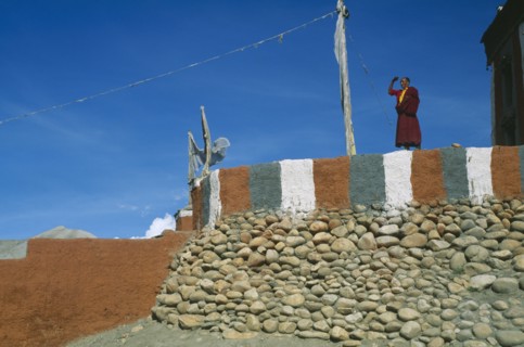 NEPAL, Mustang, Monk standing on painted terrace of Tsarang’s temple.