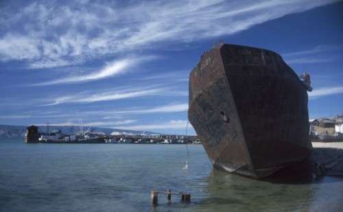 RUSSIA, Siberia, Lake Baikal, Rusting hull of ship in shallow water at lake shore.