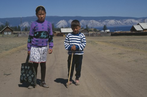 RUSSIA, Siberia, Lake Baikal, Buryat children with farmstead and lake behind.  The Buryat are of