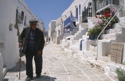 GREECE, Cyclades, Hora, Folegandros.  Street scene with elderly man using stick to walk along
