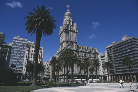 URUGUAY, Montevideo, City scene with tree lined square in foreground and mix of old and new