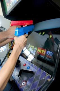 USA, Minnesota, St Paul, Teenagers shooting Point Blank video game with red and blue replica 45