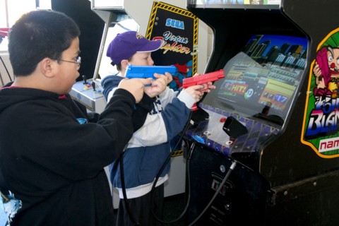 USA, Minnesota, St Paul, Kids aged 11 shooting Point Blank video game with red and blue replica 45