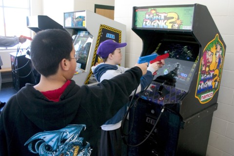 USA, Minnesota, St Paul, Kids age 11 shooting Point Blank video game with red and blue replica 45