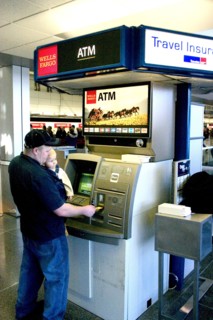 USA, Minnesota, Minneapolis, Father with baby son withdrawing cash at the ATM machine in the