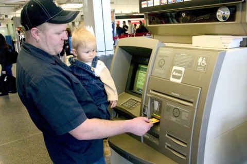 USA, Minnesota, Minneapolis, Father with baby son withdrawing cash at the ATM machine in the