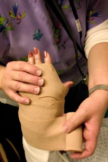 USA, Minnesota, Plymouth, Emergency room nurse wrapping temporary elastic bandage on broken wrist.