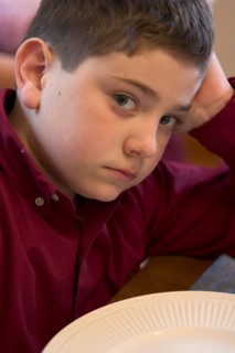 USA, Minnesota, St Paul, Defiant and hungry young boy age 8 waiting for brunch.